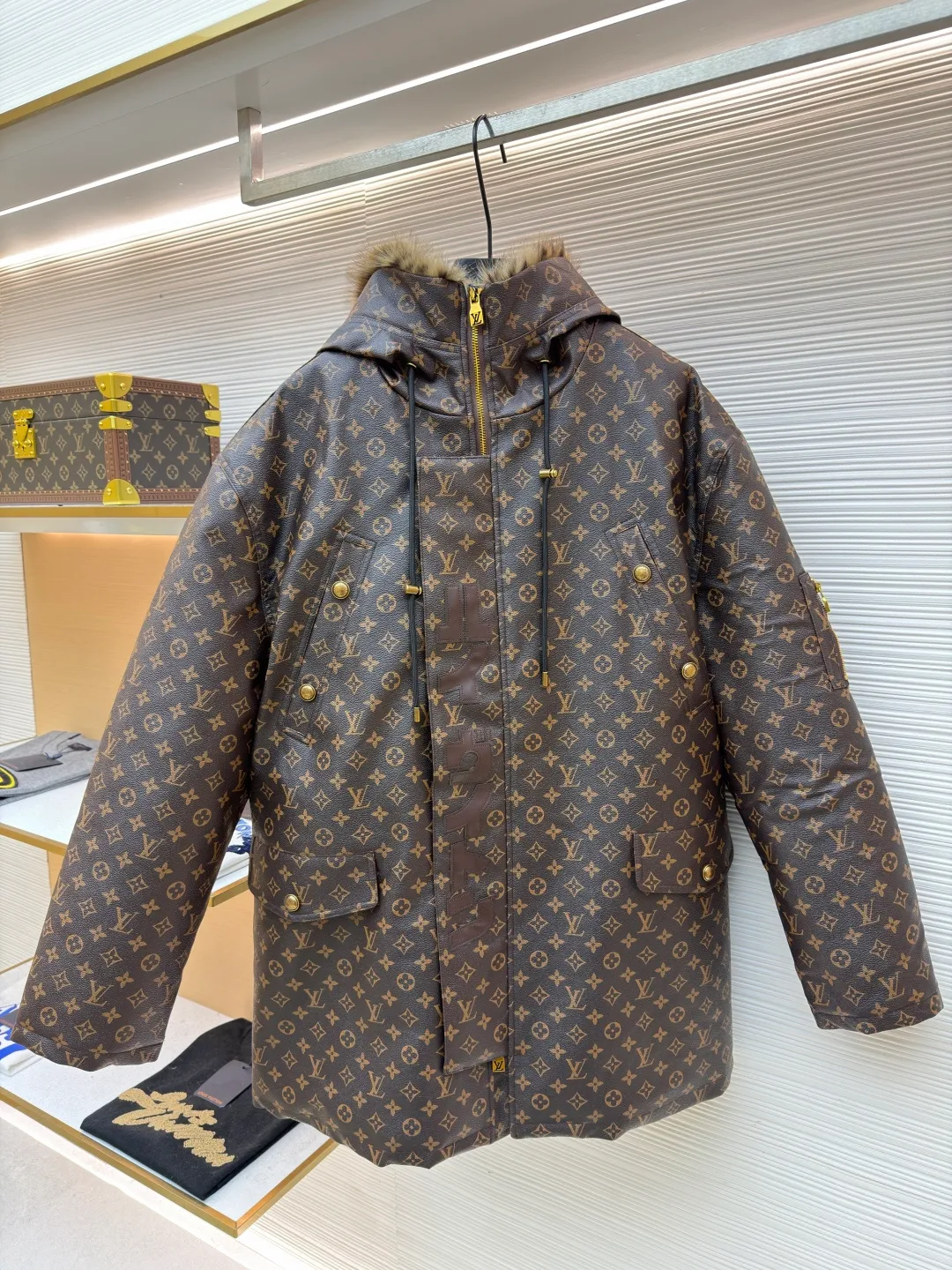LOUIS VUITTON letter print hooded jacket ●Original version: Purchased and developed for 69999 ●Item number: 1681985-E40 ●Fabric: cotton fabric ●Technology: printing production ●Color: brown ●Version: fitted version ●Weight: about 1810 grams ●Size: 46-48-50-52 ●Description: This printed jacket is made of embossed leather fabric with a dark brown base and is fully printed with the classic Monogram pattern. The embossing process gives the logo a three-dimensional texture. The edge of the hood is spliced ​​with a natural fur collar, and the brim is equipped with an adjustable drawstring (metal rope buckle) to enhance warmth and style. The placket is double-closed with a two-way metal zipper and brass snap buttons. The zipper puller and snap button are both engraved with the brand logo, which is thick and durable. The body is designed with multiple pockets, and the pockets are edged with the same material + metal snap buttons for reinforcement. The left sleeve is equipped with a hidden adjustment tab. The interior is filled with high-fill down cotton, and the stitching adopts diamond-shaped quilting technology to prevent the filling from shifting. The seams are edged with leather of the same color, and the overall wiring is precise, taking into account warmth retention and luxurious texture. The overall wiring is straight and delicate, the fabric is comfortable and soft, and the color is consistent without color difference. It can be matched with the same style to create a fashionable look and control various occasions. Customized accessories, complete with three standards, same style for men and women!
